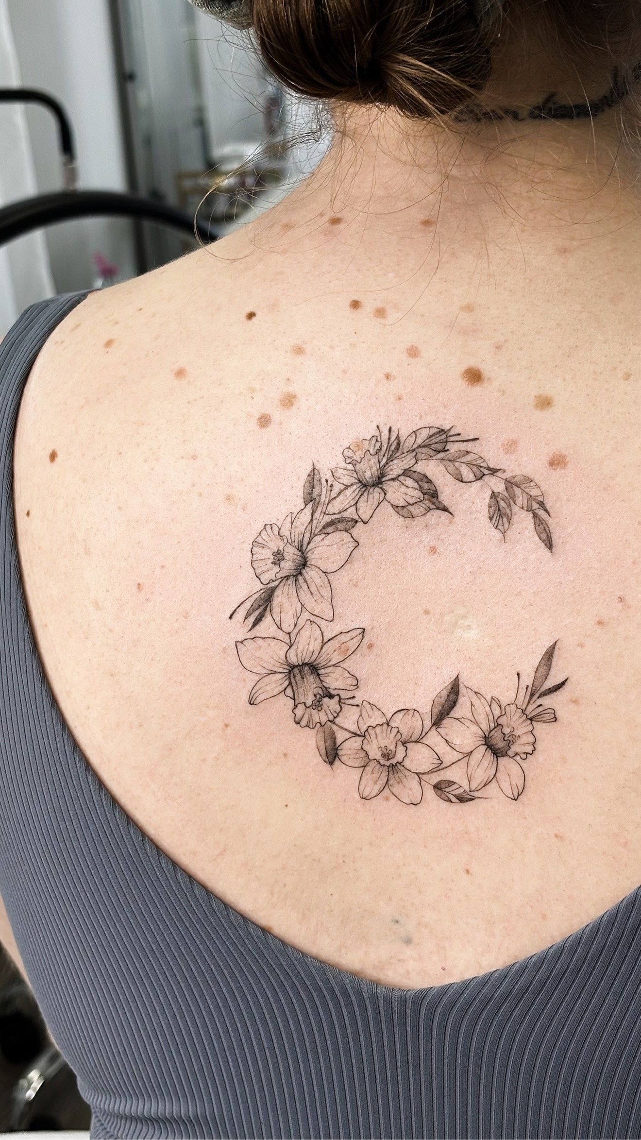 Fine line daffodil wreath back tattoo by On Point Fine Line Tattoo Studio, Woodridge IL